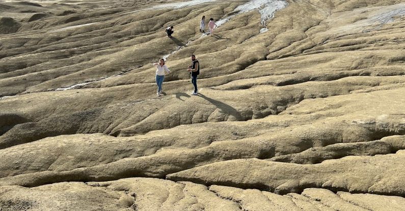 Nature Hike - People walking on a rocky terrain with mountains in the background