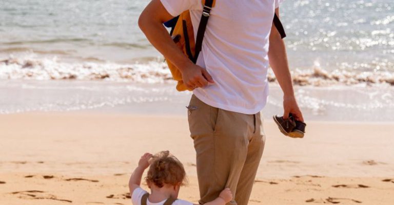 Day Trip Ideas - Happy dad looking at toddler on sandy beach