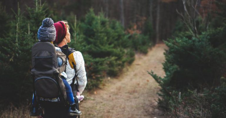 Family Hike - Shallow Focus on Blond Haired Woman in White Long Sleeve Shirt Carrying a Baby on Her Back